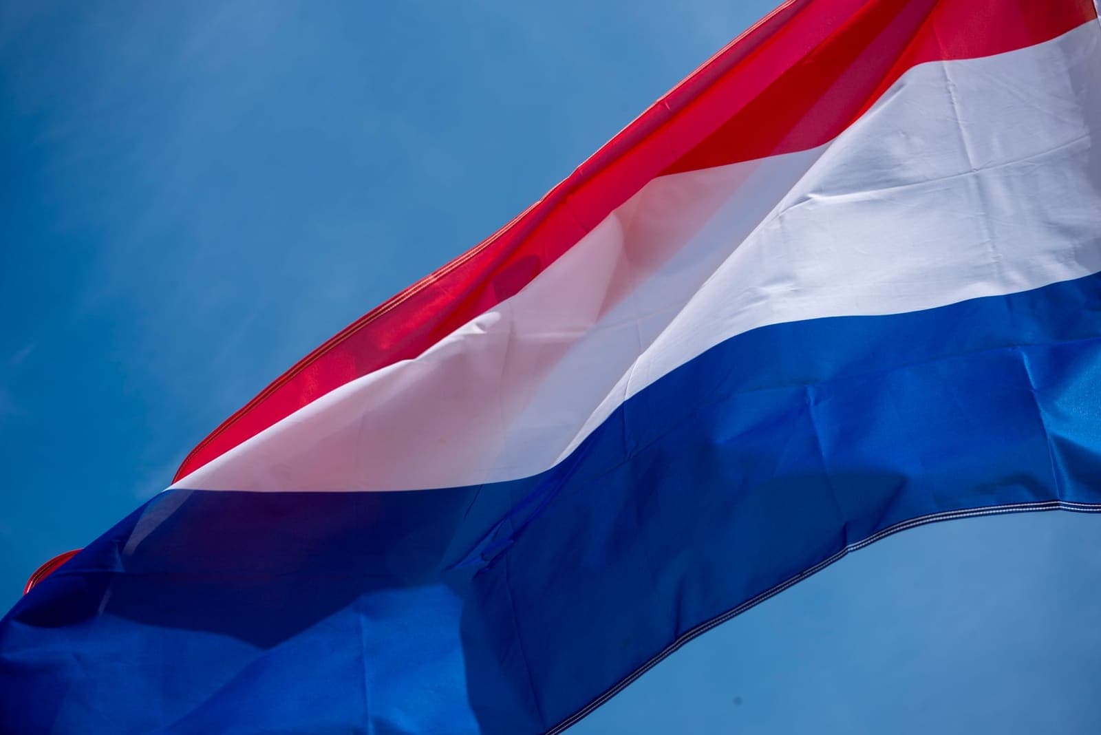 Nederlandse vlag wapperend tegen een blauwe lucht